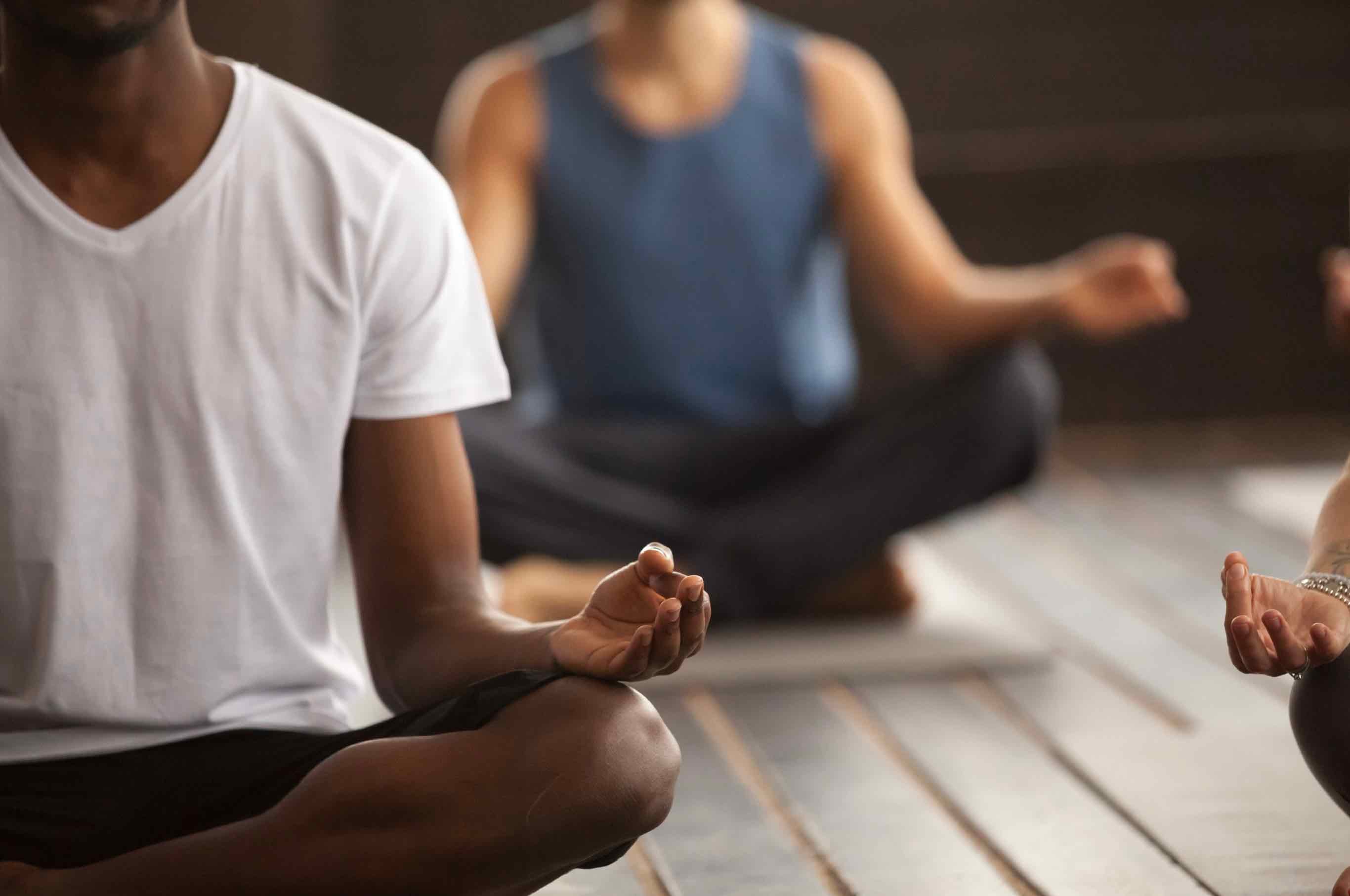 Two people practicing meditation with focus on one's hand gesture.